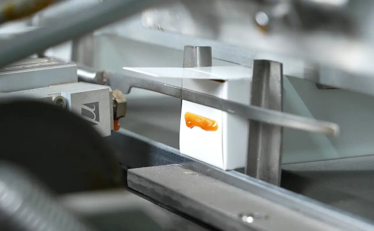 Application de colle thermofusible sur un carton de vente au détail de capsules de café